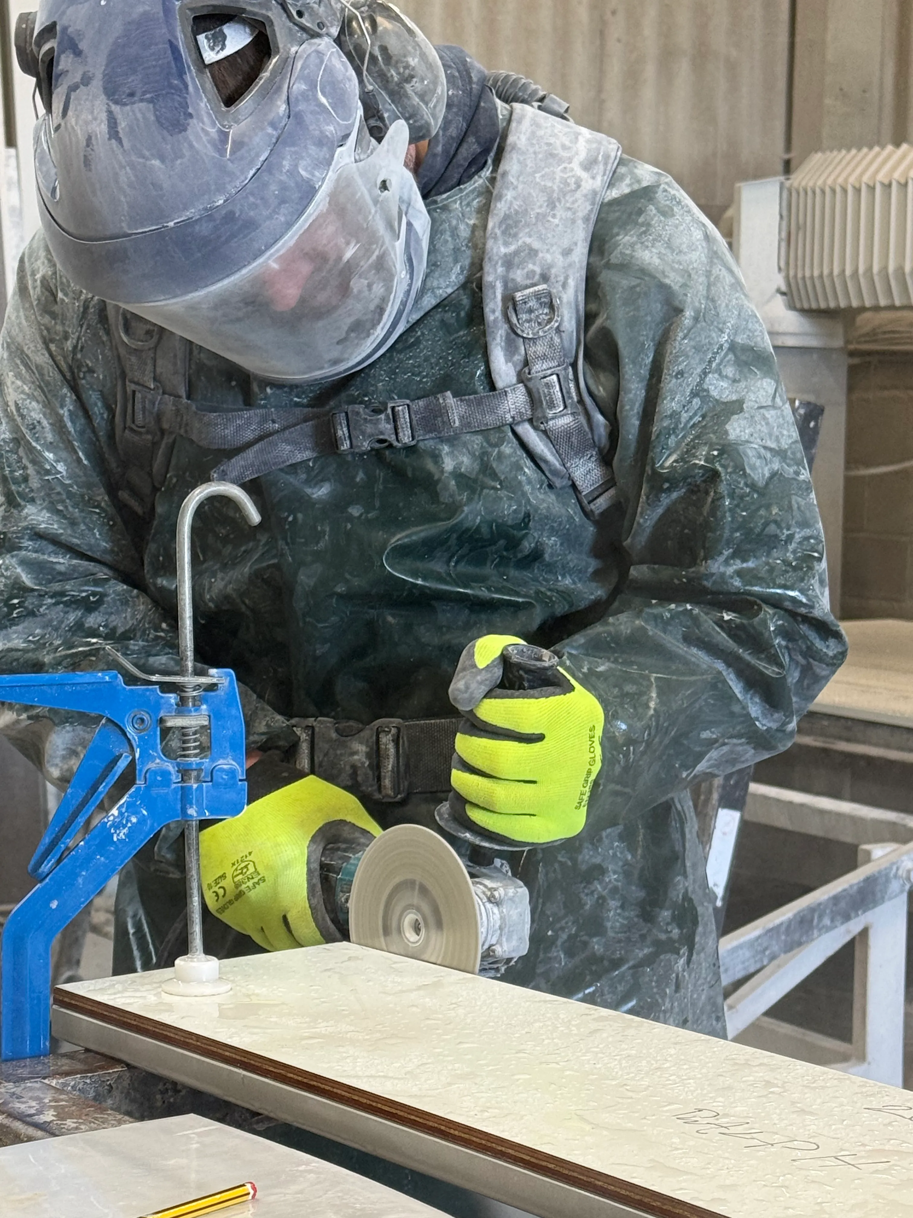 Craftsman using angle grinder to shape stone edge in the workshop