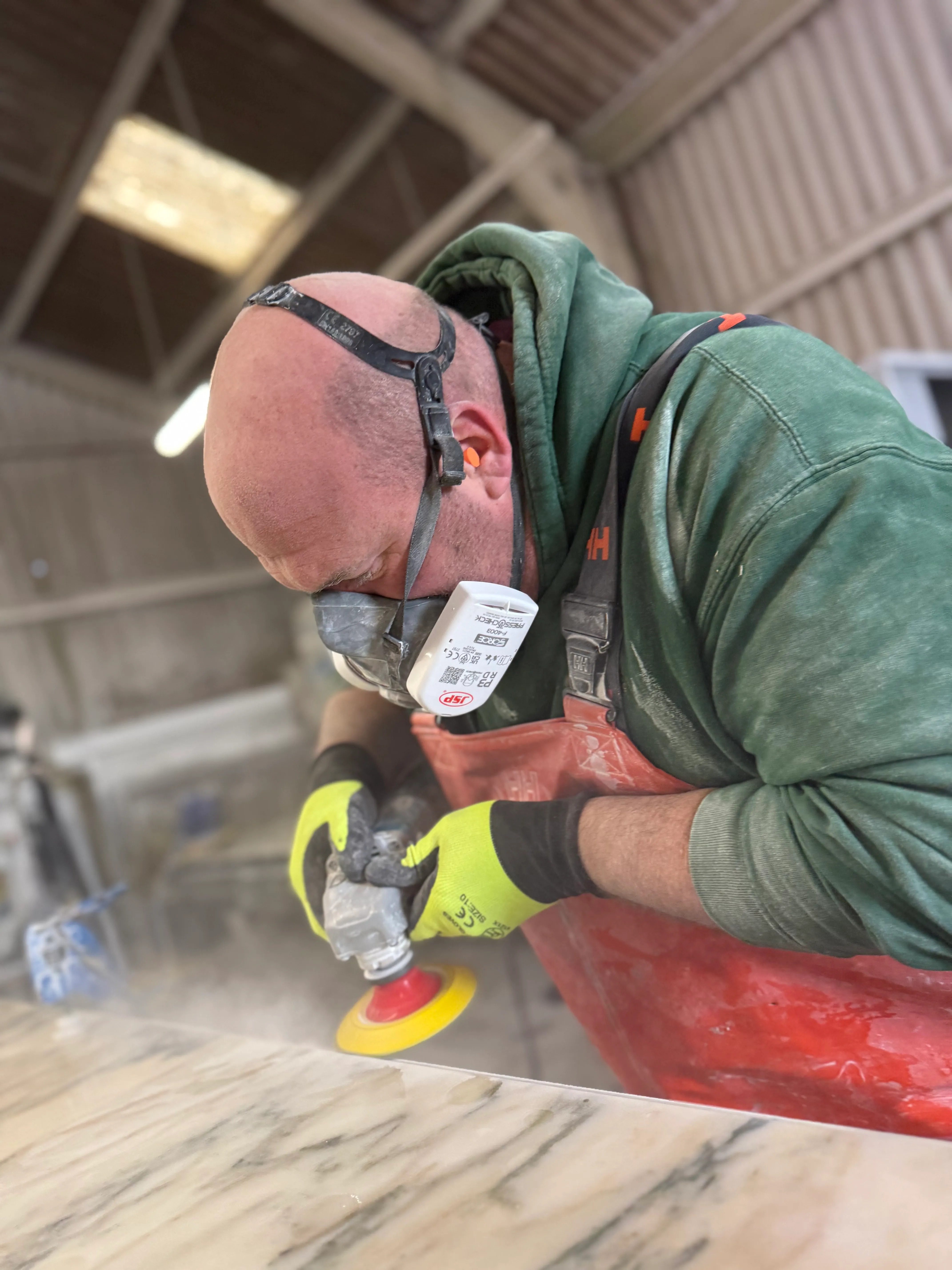 Stonemason polishing marble worktop with orbital sander